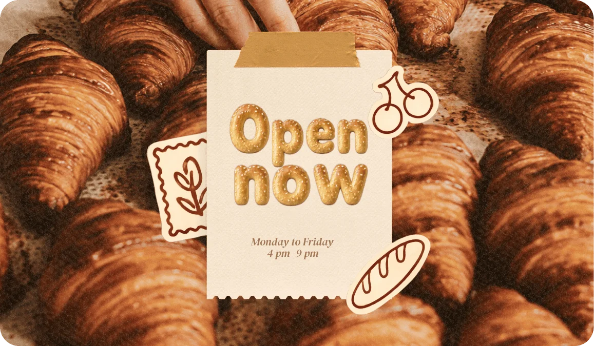 Open Now in puffy bread-textured letters on a bakery sign surrounded by fresh croissants
