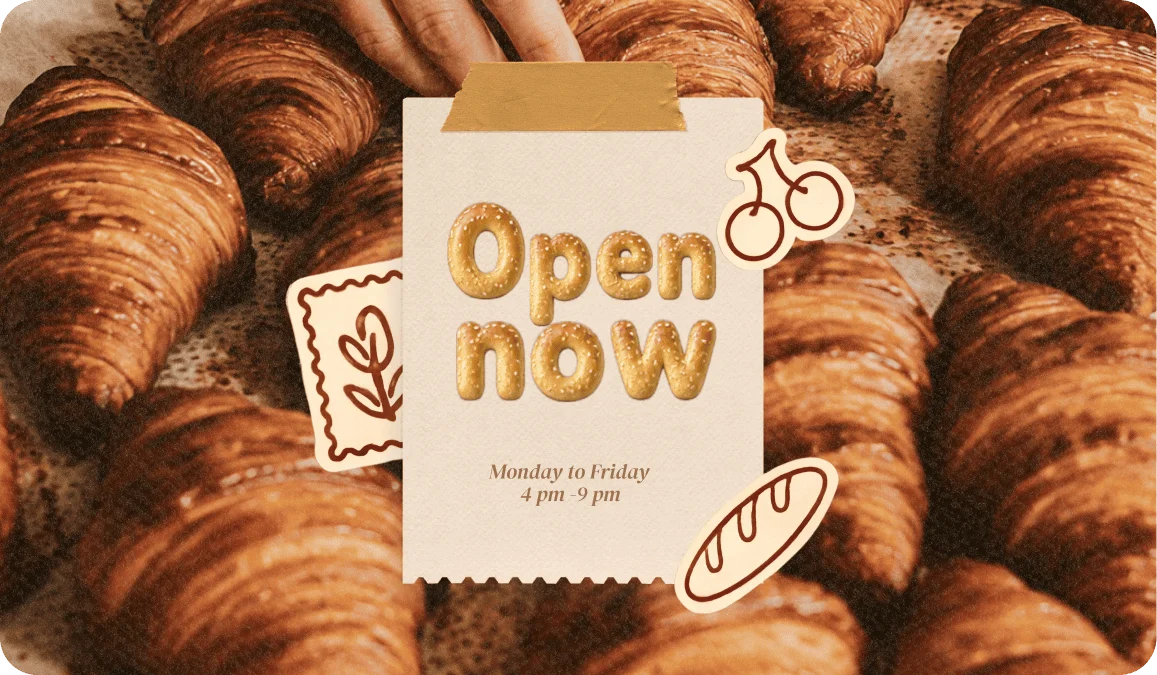 Open Now sign in puffy bread-textured letters displayed over a tray of fresh croissants